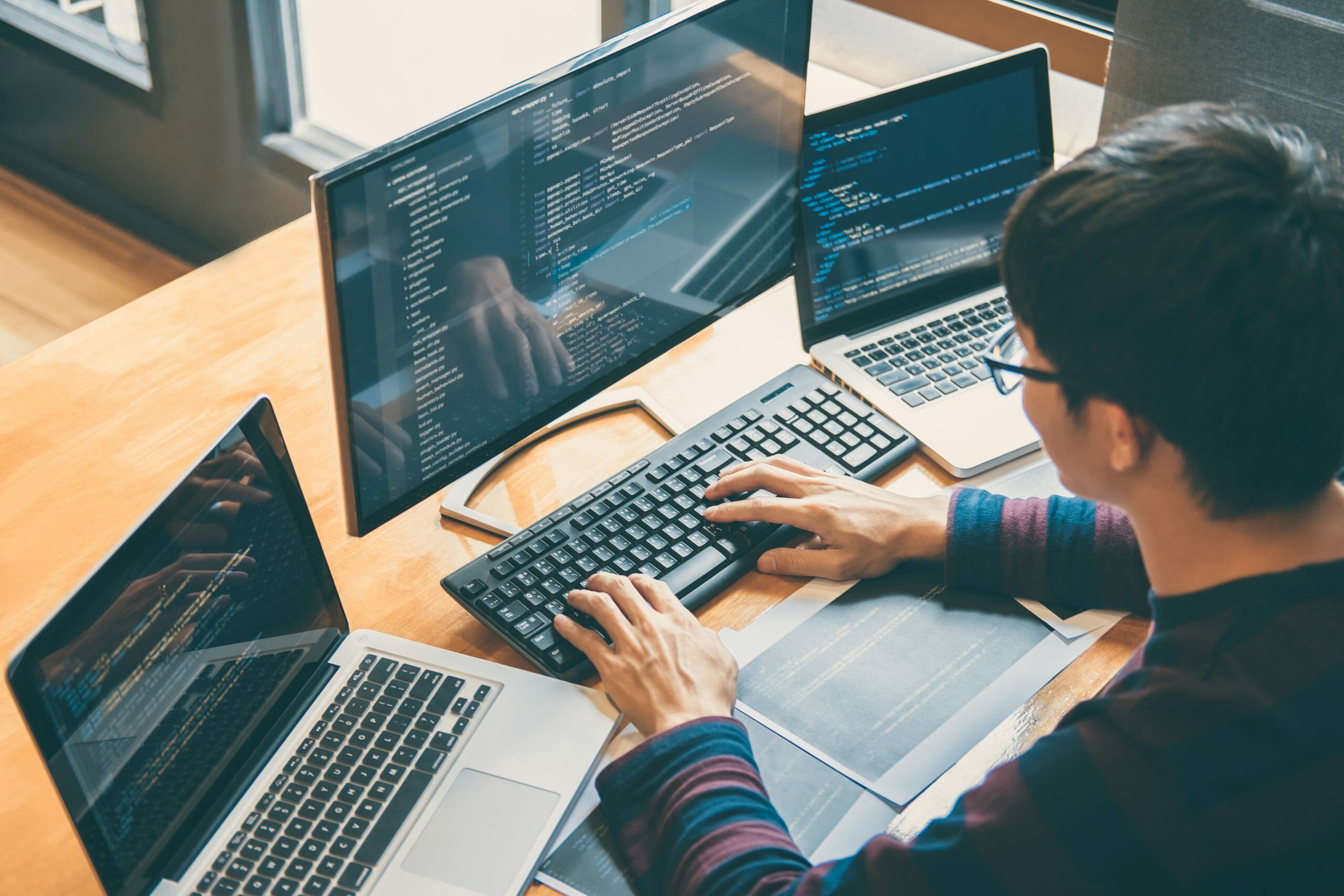 Man using three screens to program