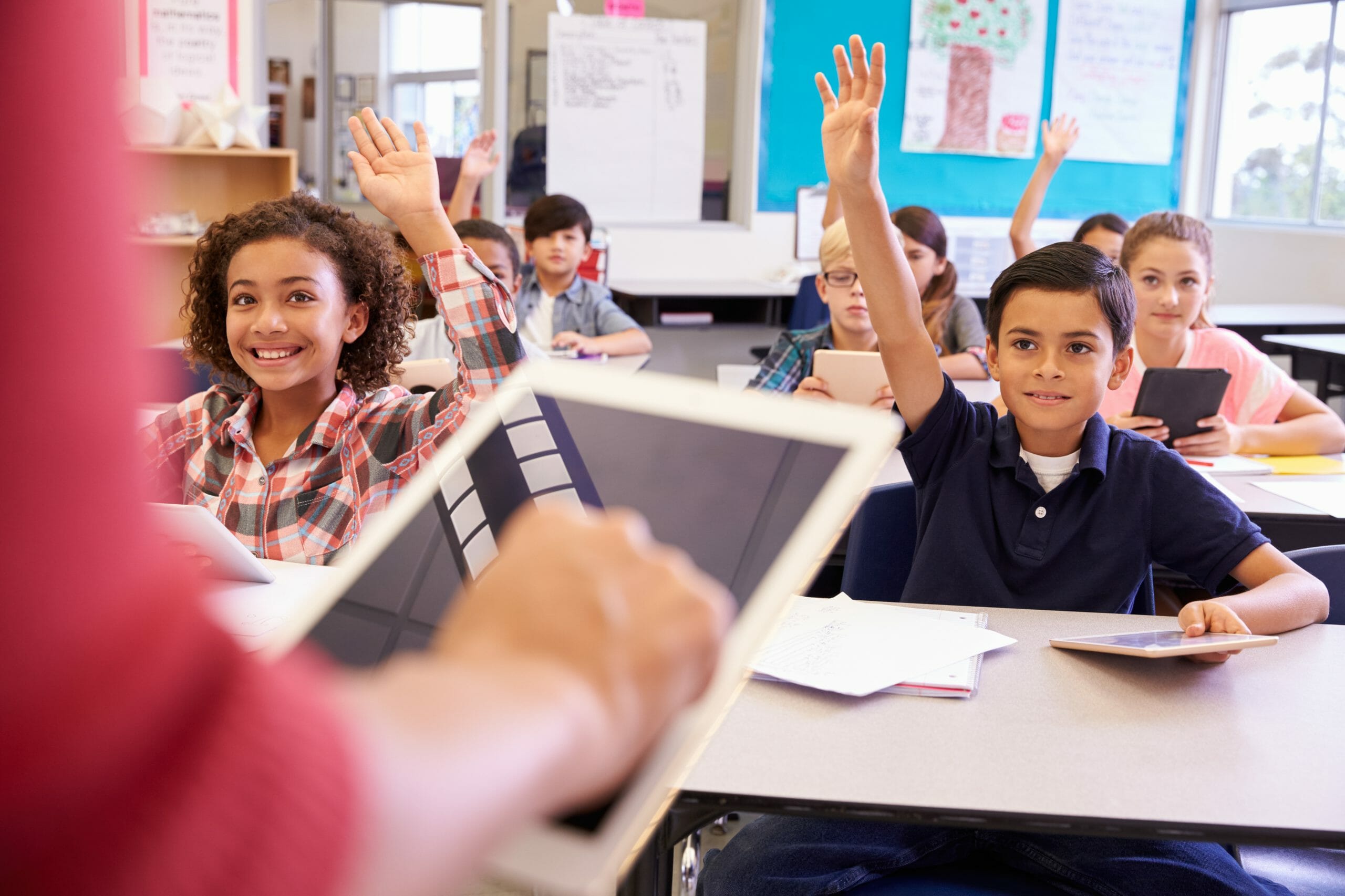 Person holding tablet speaking to classroom of kids