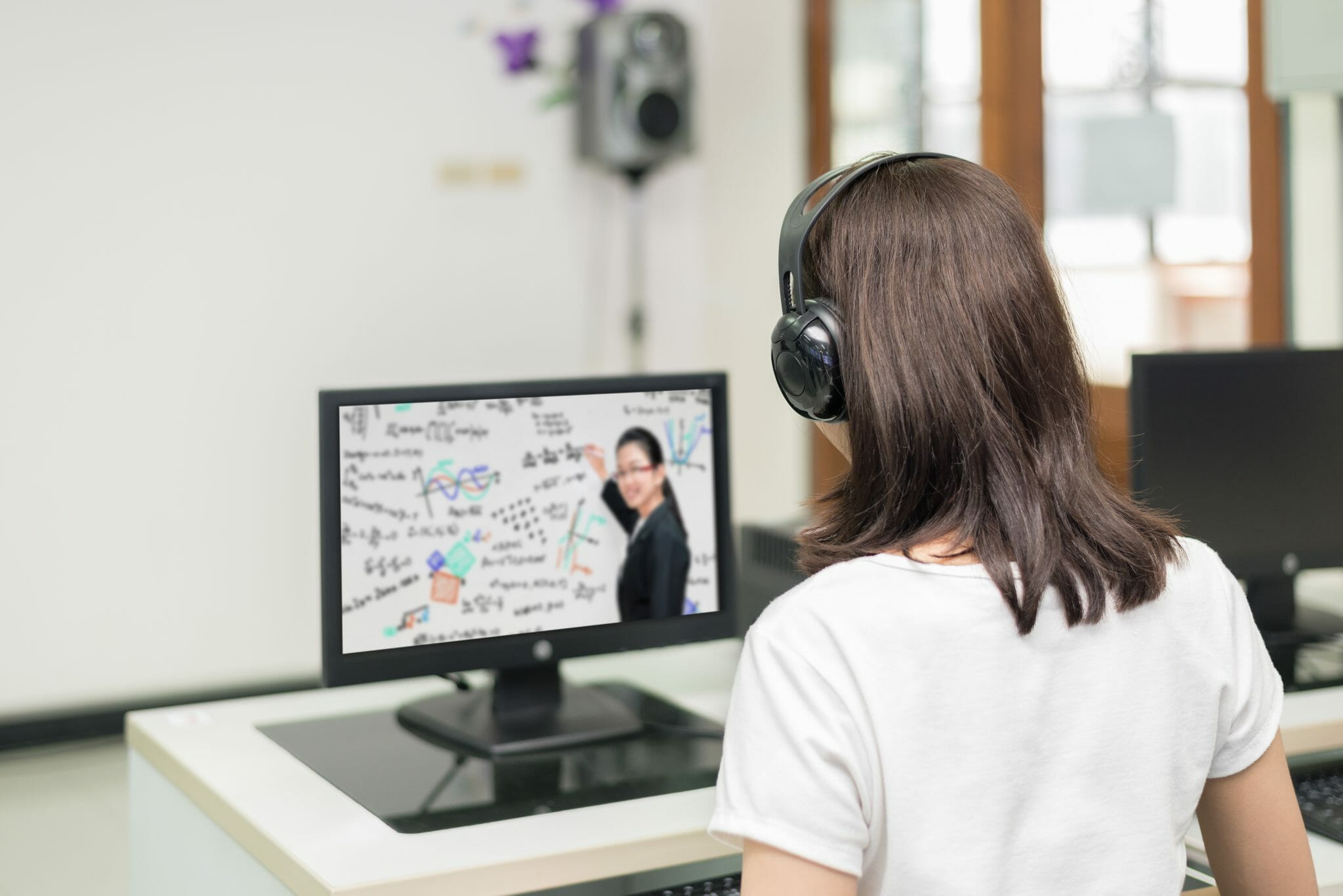 Woman with back to camera watching a video lecture