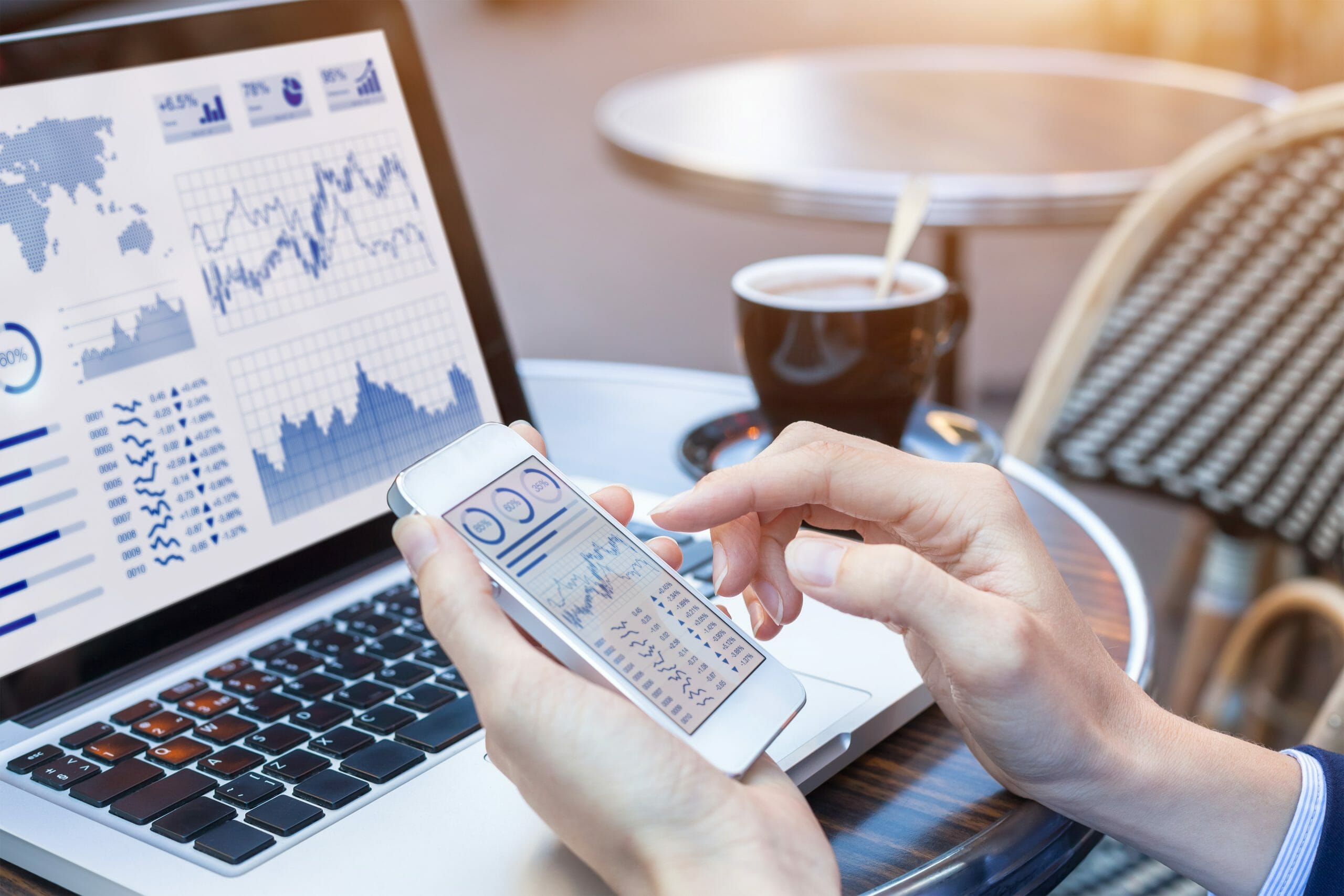 Person looking at charts on computer and phone