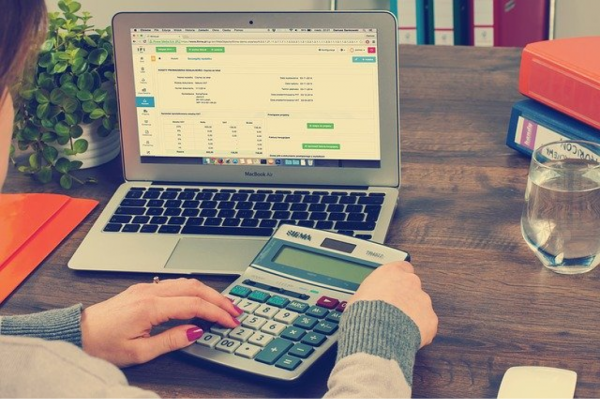 Person working at a calculator in front of a laptop